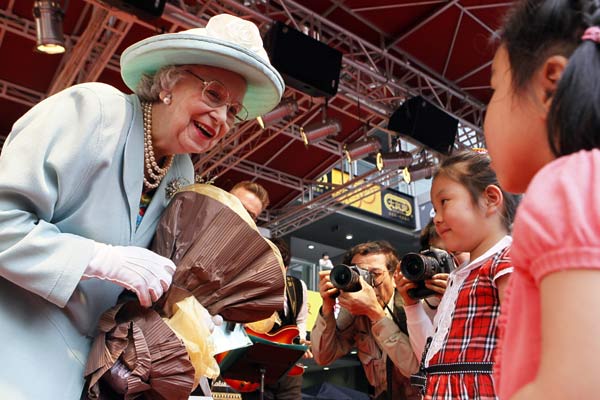 Elizabeth Richard, whao looks very similar to Queen Elizabeth II, talks to children at a tea party to promote the Queen's Diamond Jubilee at the Daning International Business Plaza in Shanghai on Tuesday. Yong Kai / for China Daily Costs deter Chinese from UK Olympics