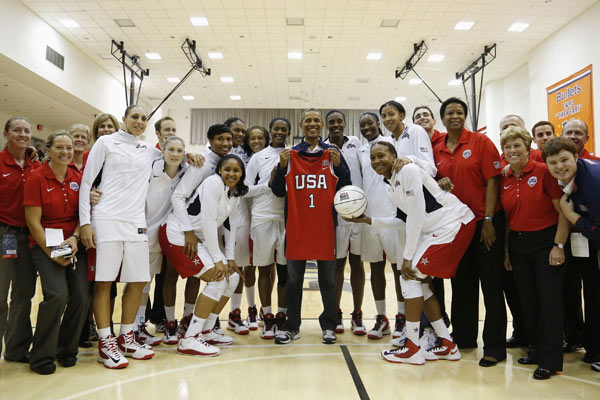 US President Barack Obama (C) holds a jersey given to him by members of the US Olympic women's basketball team after their exhibition game against Brazil in Washington, July 16, 2012. Obama cheers for US Olympic basketball team