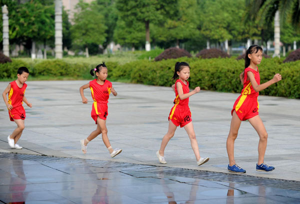 A four-member race-walking team has been training every day at the Anfu Square since 2010. They are instructed by Zou Guilin, a 51-year-old coach who is also the first trainer of the famous Chinese race walker Liu Hong. Children walk toward Olympic dreams