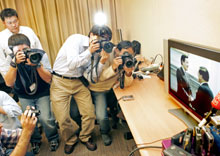 Local journalists watch and photograph a closed circuit television as Taiwan's President Chen Shui-bian (R) greets main opposition Nationalist Party leader Ma Ying-jeou at the Presidential Office in Taipei April 3, 2006.