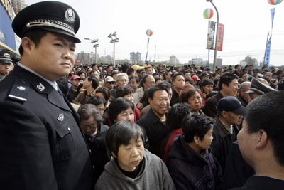 A Chinese policeman watches as customers surge during the opening of Ikea store in Beijing April 12, 2006. Sweden's IKEA, the world's largest furniture retailer, said it planned to triple the number of stores in China over the next three to four years, as lower prices help fuel an ambitious global expansion plan.