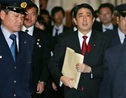 Japanese Prime Minister Shinzo Abe (R) is escorted by guards as he arrives at the Upper House plenary session at the parliament in Tokyo October 4, 2006. Abe will visit China on October 8 and South Korea the next day for talks with their leaders in a bid to repair ties frayed by disputes over their bitter wartime past, but North Korea's nuclear threat looks set to grab a prominent place on the agenda.
