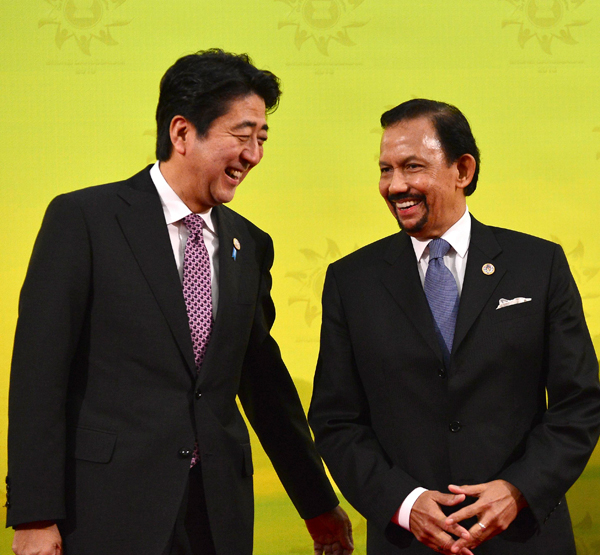 Japan's Prime Minister Shinzo Abe (L) laughs with Brunei's Sultan Hassanal Bolkiah before the family photo at the 16th ASEAN-Japan Summit in Bandar Seri Begawan, October 9, 2013. ASEAN welcomes Japan's stronger involvement in bloc