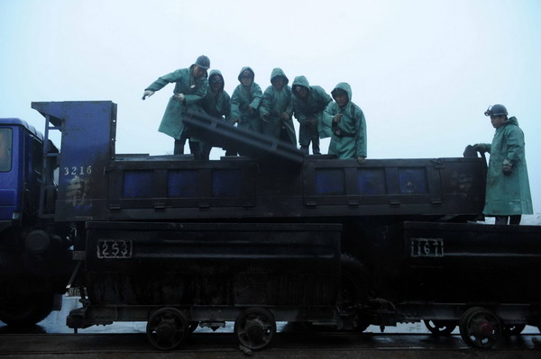 Rescue workers unload a truck in the rain in Yima, Henan province, Nov 4, 2011, after a rock burst at Qianqiu Coal Mine killed four miners and trapped 57 others. 4 killed, 50 trapped in coal mine