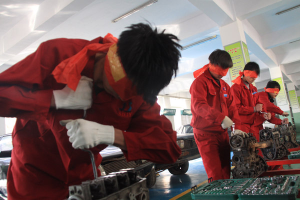 Students compete in the skills needed to handle a machine with their eyes covered at the No 2 Vocational School of Jinan, Shandong province, on Feb 18. Chen Ning / for China Daily Help to vocational schools aids students