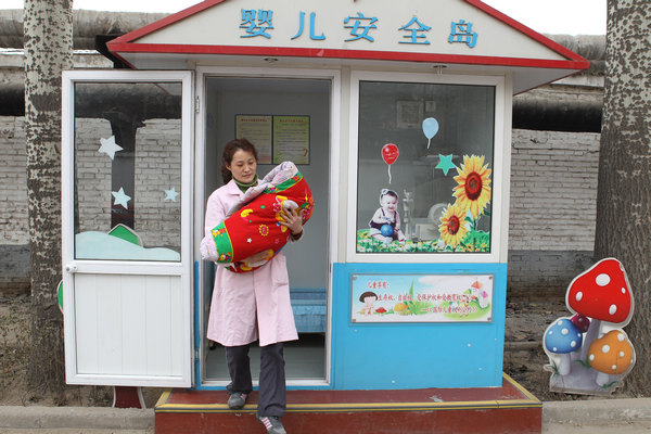 Yang Li, an employee of the Shijiazhuang Social Welfare Institute, carries a 1-month-old abandoned baby out of the 'safe haven' set up by the institute on June 1, in Shijiazhuang, capital of Hebei province, on Thursday. Feng Yongbin / China Daily Newborns' haven sparks debate