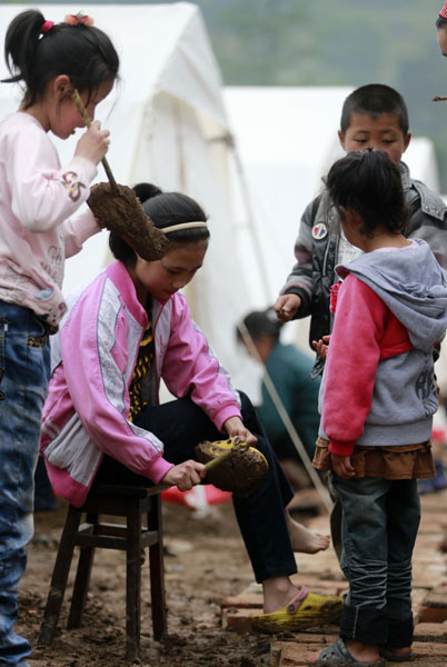 Children attempt to clean mud from their shoes in a makeshift shelter in Fujiaying village. Disaster: Self help and survival