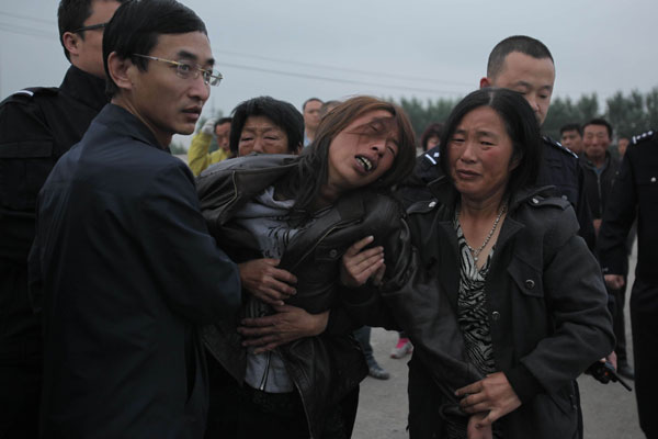 A woman who loses her relative grieves outside a poultry factory that caught fire and claimed 120 lives, in Jilin, June 4, 2013. Poultry plant fire death toll rises to 120