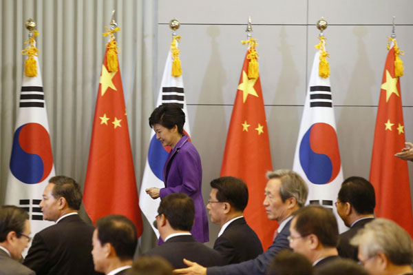 South Korea's President Park Geun-hye walks past flags of China and South Korea after delivering an address at Tsinghua University during her state visit to China in Beijing June 29, 2013. President Park inspires students