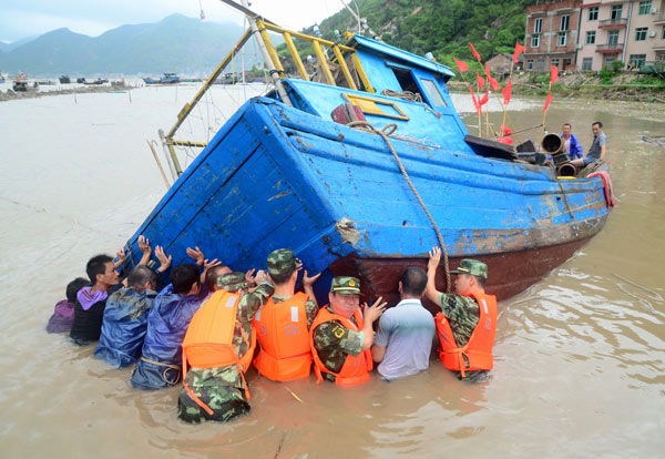 Troops and fishermen try to move a boat to a safer spot in Xiapu, Fujian province, on Thursday, after it was overturned by the powerful winds of Typhoon Trami. Yuan Ziyou for China Daily Trami batters southern China