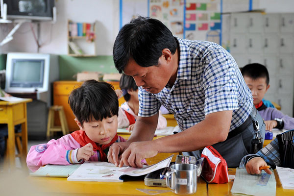 Rural teacher Fan Meisuo helps a girl with her study in Changning town, North China's Shanxi province, Sept 4, 2013. Plan to change Teacher's Day stirs debate