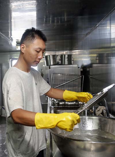 Li Penghui, one of 15 galley assistants, at work aboard the Peace Ark. Zhang Hao / for China Daily When life is sailing over the bounding sea