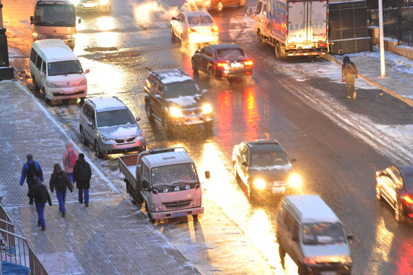 Vehicles move along a street amid snow in Dalian, Northeast China's Liaoning province, Dec 19, 2013. Blizzard in NE China closes 10 expressways