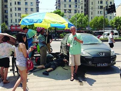 騎車(chē)男被卷入轎車(chē)輪下 路人抬起轎車(chē)救人(圖)
