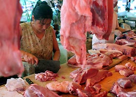 A vendor prepares pork at a market in Shanghai yesterday. ChinaåK½s far south is on high alert since one person was killed and three infected by a pig-borne disease that had left nearly 40 dead in the southwest. The latest person killed by the disease, caused by the Streptococcus suis bacterium, had handled infected pork, Xinhua news agency said on Tuesday. The three other victims, all butchers, also likely had contact with infected meat.