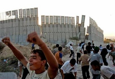 Palestinian youths throw stones over a fence of Jewish settlement of Neve Dekalim, from Khan Younis in the southern Gaza Strip September 11, 2005.