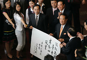 James Soong (holding the inscription, centre), chairman of People First Party in Taiwan, shows his inscription describing his feelings upon finishing a visit to the Shanghai Urban Planning Exhibition Centre shortly after his arrival in the East China metropolis yesterday afternoon. Soong was in Shanghai to attend the Cross-Straits Non-governmental Forum of Elites, which opens today. Gao Erqiang