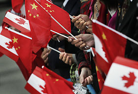 People gather at the airport holding Chinese and Canadian flags while waiting for the arrival of Chinese President Hu Jintao in Vancouver, British Columbia, September 16, 2005.