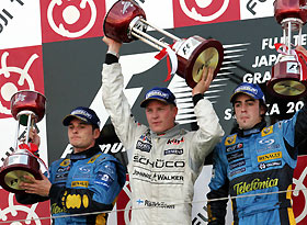 McLaren's Formula One driver Kimi Raikkonen of Finland raises his trophy on the victory podium after winning the Japanese Grand Prix at the Suzuka Circuit in central Japan October 9, 2005. At left is Renault's Giancarlo Fisichella, who finished second, and at right is his Renault team mate Fernando Alonso of Spain in third place.