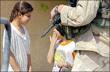 Iraqi girls talk to each other as a US soldier from A/1/112 company infantries patrols a street in the city of Tikrit, north of Baghdad.