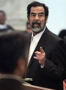 Saddam Hussein again grabbed center stage at his mass murder trial Wednesday, suddenly standing up and surprising the courtroom with claims that he and other defendants were "beaten by Americans."