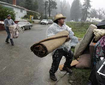 Workers throw out carpet and furniture from a house that was flooded in Guerneville, California, January 3, 2006. Two powerful storms over the weekend swelled rivers and caused flooding, mudslides and evacuations across Northern California resulting in an estimated tens of millions of dollars in damage.