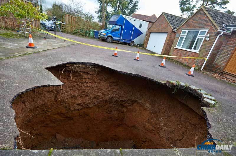 英國居民房屋前驚現(xiàn)大坑 汽車慘遭“吞噬”