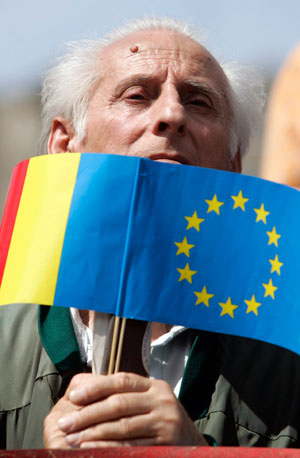 An elderly man holds European Union and Romanian (L) flags during a ceremony marking Europe Day and World War Two Victory Day in Bucharest May 9, 2007. New European Union (EU) member Romania celebrated on Wednesday EU's 50th birthday and the 62nd anniversary of World War Two victory over Nazi Germany.