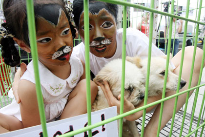 Animal rights activists, dressed up as dogs, pose with dogs inside a dog cage during a protest against the eating of dog meat in central Seoul July 25, 2007. In the summer, many Koreans traditionally eat dog meat for good health to overcome hot weather.