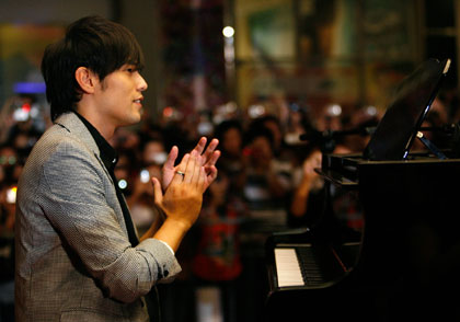 Singer and actor Jay Chou of Taiwan applauds for a fan who performed before the premiere of his new film