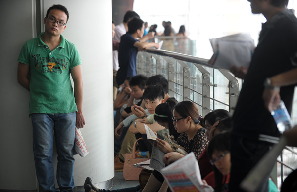 College graduates take a break at a job fair in Chongqing in May. The fair offered 20,000 vacancies at 500 businesses. Yu Xiao / for China Daily Graduates face grim hunt for work
