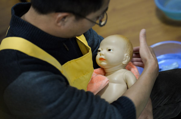 Li Dabin trains with a toy baby in Changsha, Hunan province on Dec 1. From college teacher to maternity matron