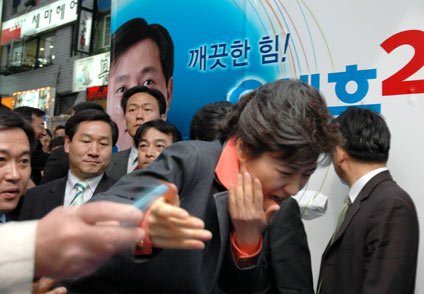 An unidentified man, whose hand is seen on left in this photo, uses a penknife to assault Park Geun-hye, leader of South Korea's main opposition Grand National Party during a campaign for local elections in Seoul May 20, 2006. Park suffered a 10-cm cut on the right side of her face after the assault, local media reported.
