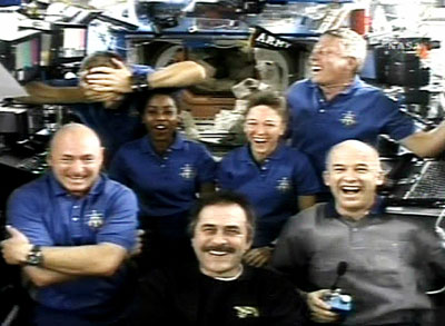 Piers Sellers (top, L) covers his head as his crewmates laugh after he was described as the spacewalker who lost the spatula during a crew news conference from aboard the International Space Station in this view from NASA TV July 14, 2006. The members of the crew are front row (L-R) Pilot Mark Kelly, ISS Commander Pavel Vinogradov, Jeff Williams, and back row, Sellers, Stephanie Wilson, Lisa Nowak and Mike Fossum.