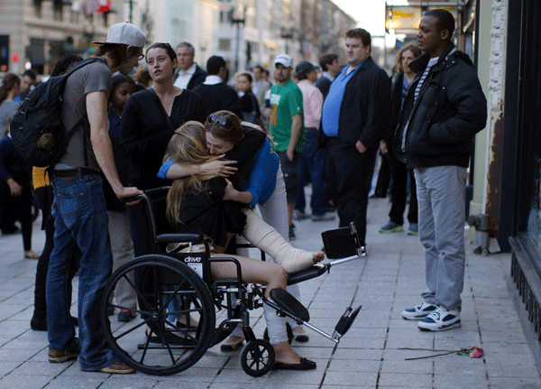 A Boston Marathon bombing survivor receives a hug next to the site of the first bomb explosion on Boylston Street in Boston, Massachusetts, April 24, 2013. Boston bombs set off by toy remote