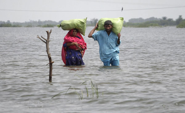 A couple carry their belongings as they wade through flood waters in the village of Ali Nawaz Khuso, Badin district of Pakistan's Sindh province Sept 14, 2011. 300,000 homeless due to flood in Pakistan
