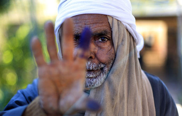 An elderly Egyptian man shows his inked finger after casting his vote in the second round of a referendum on a disputed constitution drafted by Islamist supporters of President Mohammed Morsi in Fayoum, Egypt. Khalil Hamra / Associated Press Egyptian president signs new constitution