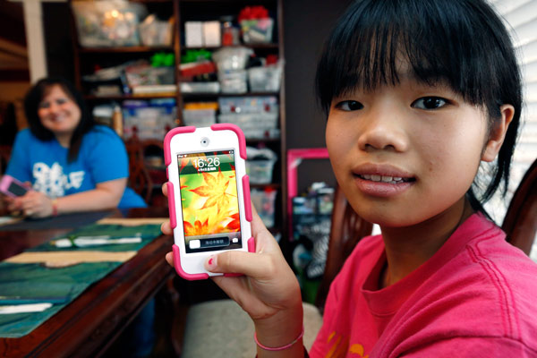 Guan Ya Smith, 14, who is deaf, shows off her iPod that allows her to communicate with her new adoptive family through Google Translate. Phillip and Niki Smith (background) and their three other children in Rienzi, Mississippi, use the program to speak with Guan Ya. Rogelio V. Solis / Associated Press Online translator breaks down language barriers