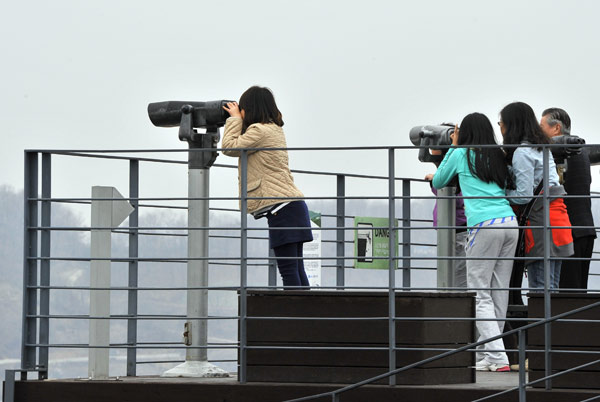Visitors look toward the DPRK at a park near the demilitarized zone between the ROK and the DPRK, in the border city of Paju. Jung Yeon-Je / Agence France-Presse Curious tourists head to border despite threats