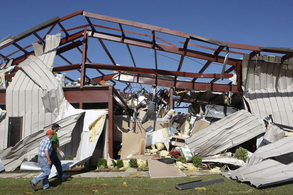 Men walk near OKC-West Stockyards Livestock Market, which had its roof and walls blown off by a tornado, near El Reno, Oklahoma, June 1, 2013. Oklahoma tornadoes kill at least nine