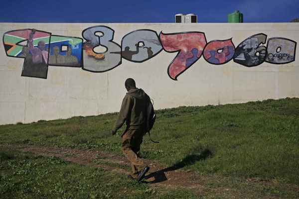 A man walks past a mural depicting former South African President Nelson Mandela and his role in the country's liberation, in Cape Town, June 10, 2013. Mandela hospitalized over 60 hours