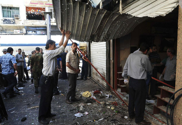 People gather at the site after bombs exploded close to a police post in the central Marjeh Square in Damascus June 11, 2013, in this handout photograph distributed by Syria's national news agency SANA. Twin blasts kill 14 in central Damascus