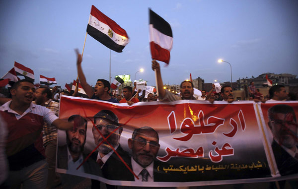 Protesters opposing Egyptian President Mohamed Mursi shout slogans near a banner with pictures of Muslim Brotherhood members during a demonstration in front of the Presidential Palace 'Qasr Al Quba' in Cairo July 2, 2013. Mursi defies army as it plots future without him