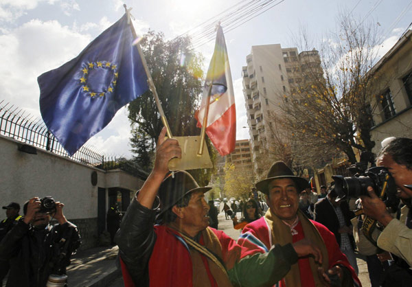 An Aymara man holds the flags of the European Union and France after removing them from the wall of the French embassy in La Paz, in protest against the French government's ban of Bolivian President Evo Morales' plane in its airspace, July 3, 2013. Snowden still in Moscow despite Bolivian plane drama