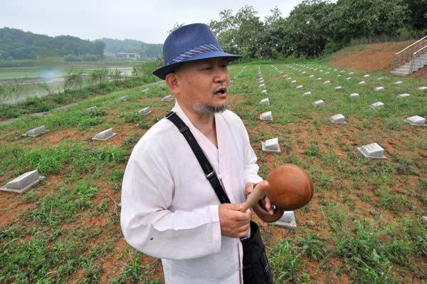 To honor soldiers from the Democratic People's Republic of Korea who died during the Korean War (1950-53), Mukgai, a monk from the Republic of Korea, bangs a wooden gong at a cemetery in Paju, ROK. Jung Yeon-Je / Agence France-Presse Monk tends graves of 'exiled' troops