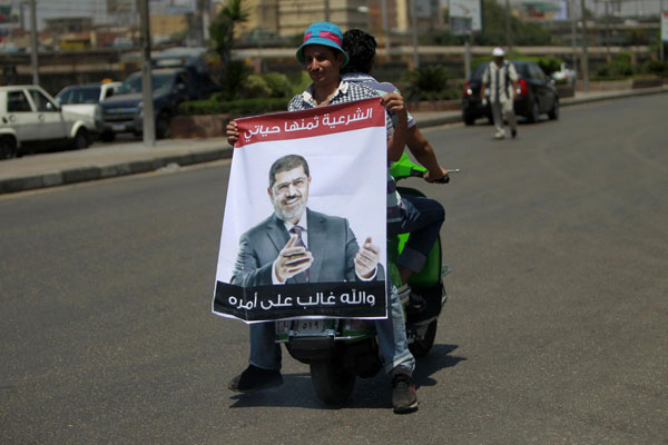 A supporter of deposed Egyptian President Mohamed Mursi holds a poster of him as he rides on a scooter during a march from the Al-Fath Mosque to the defence ministry, in Cairo July 30, 2013. Egypt allows EU envoy to see deposed Morsi