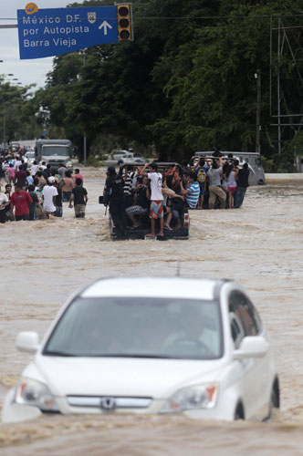Vehicle carry people in a flooded avenue in Acapulco, Guerrero, Mexico, on Sept 17, 2013. Death toll of storms rises to 47 in Mexico